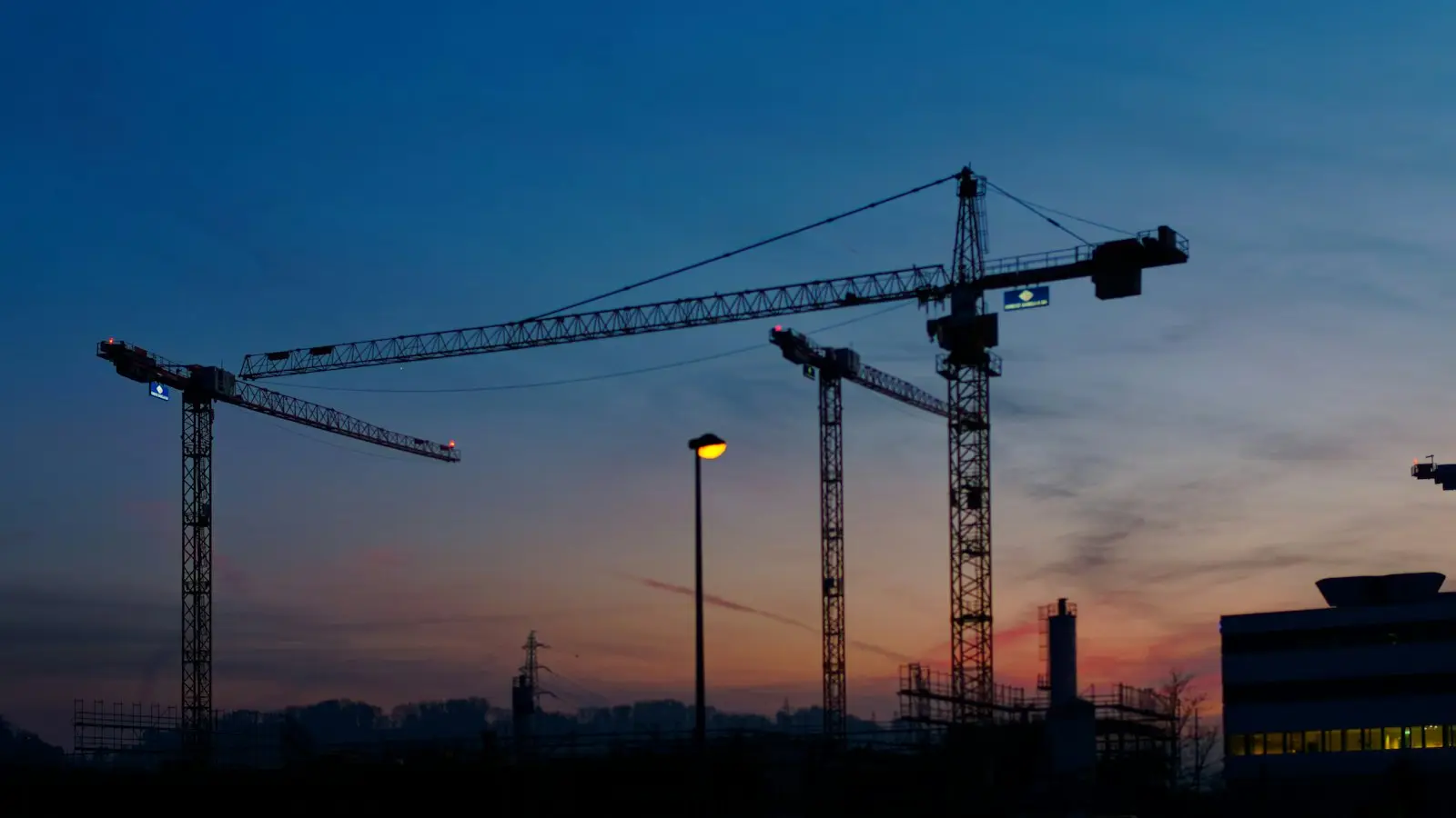 Grúas sobre torres en estructura al atardecer
